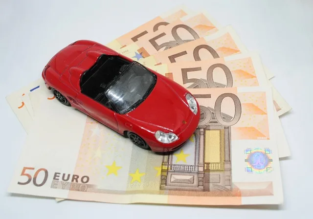 Voiture miniature rouge posée sur des billets en euros représentant le coût de l'assurance auto au Portugal