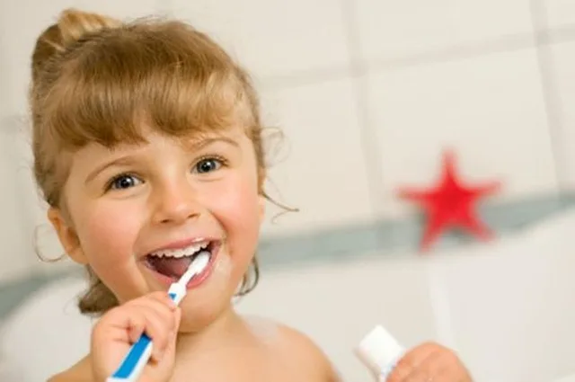 Petite fille souriante qui se brosse les dents